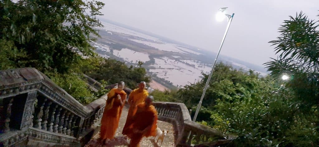 Buddhist monks in orange climbing a stairway